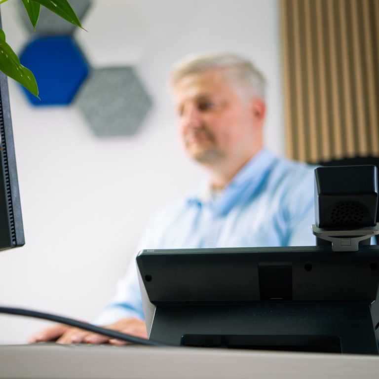 Mann im Büro, arbeitet an einem Computer mit moderner Ausstattung.
